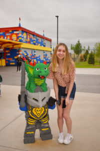 girl poses next to a lego statue of a dragon on a knight's head, one of the many lego displays at legoland New York resort