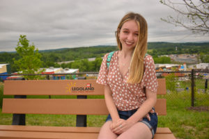 girl sits on a legoland New York bench with views of the Hudson Valley and the lower half of the park in the background