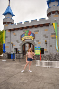 girl stands in front of castle-themed entrance to the dragon, a kiddie coaster at legoland New York resort