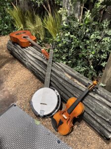 A guitar, banjo, and violin propped against a log in the Sinners haunted house set