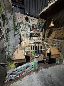 A weathered, armored off-road vehicle inside the MADLANDS: Caged Cannibals haunted house set