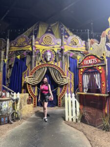 Guest posing at the carnival tent entrance of Jack & Oddfellow: Chaos & Control during the Behind the Screams tour