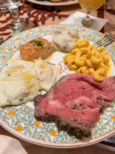 Buffet dinner plate from Storytellers Cafe with sliced prime rib, mac and cheese, mashed potatoes, salmon, and ravioli.