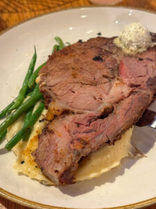 Boatwright's roasted prime rib over mashed potatoes, served with green beans and garlic butter dollop